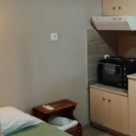 Studio apartment interior with mini kitchen and bed at Prosforio Rooms in Halkidiki.
