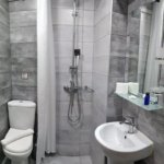 Modern bathroom interior at Prosforio rooms in Ouranoupoli Halkidiki Greece, with grey tiles, shower, toilet, and sink.