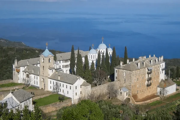 Panoramic view of the large Prodromos Romanian Skete with its distinct silver domes, surrounded by greenery near the sea in Mount Athos, Greece.