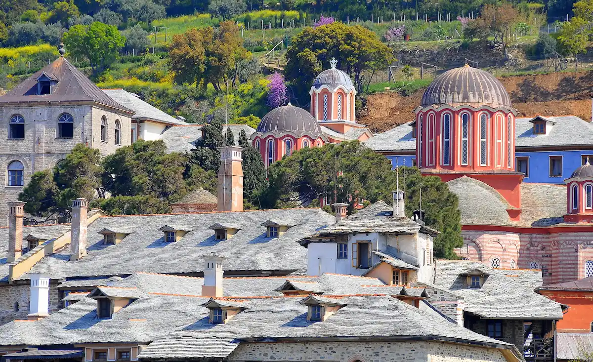 View of Xenophontos Monastery in Mount Athos featuring red domes and traditional stone roofs.